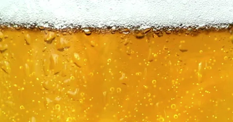 Bubbles movement inside a glass of beer with drops and foam as background Видео 60402910