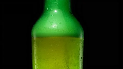 Bubbles rise up and foam inside the green beer bottle. Stock Footage 155355524