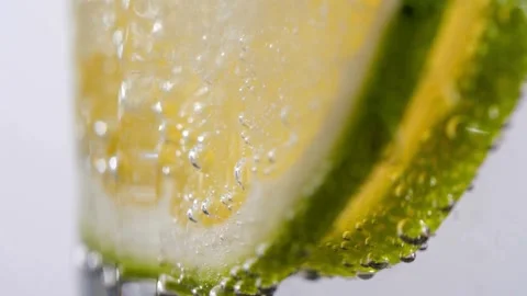 Bubbles rise around lemon and lime slices in water Vídeo Stock 332284251