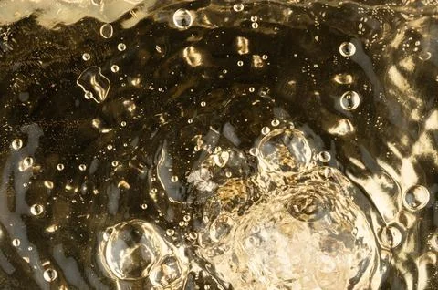 Bubbles rise in clear liquid as they form and pop on the surface Stock Photos
