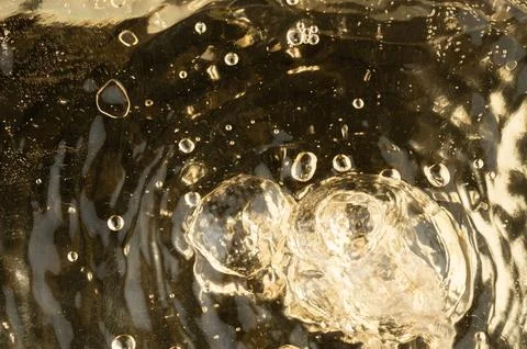 Bubbles rise in a clear liquid within a glass container 库存照片
