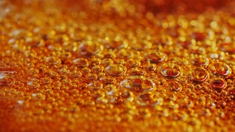 Bubbles rising in boiling thick, amber-brown liquid making an abstract Vidéo 138530776