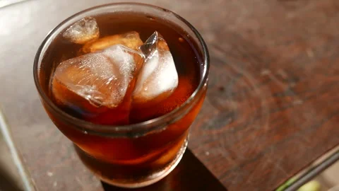 Bubbles of soda rising in a glass on the table.  A cola soda. A glass of soda Stock Footage 330383972