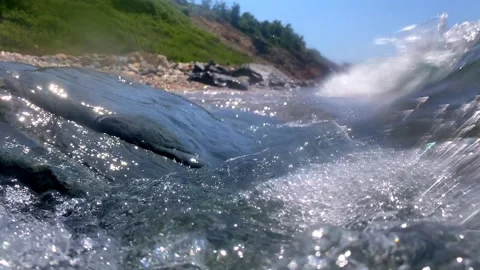 Bubbles stream upward and sideways through fast-moving water, pushed by strong Stock Footage 314665025