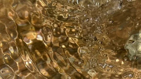 Bubbles on the surface of clear, sparkling, flowing water reflecting sunlight Stock Footage 76802535