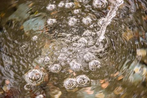 Bubbles at the surface of the water made by a trickle of water Stock Photos