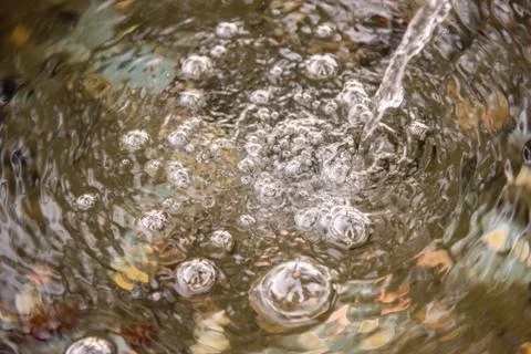 Bubbles at the surface of the water made by a trickle of water Stock Photos