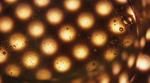 Bubbles suspended in moving liquid above lights Stock Footage 37989725