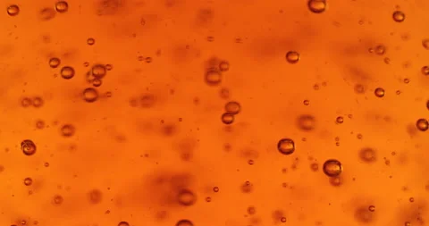 Bubbles in the yellow liquid are slowly rising and bursting. Oil, beer or honey Stock Footage 130253200