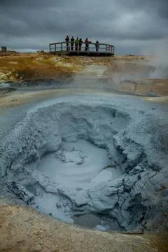 Bubbling geothermal hot mud pool in the Hverarond, tourists are watching a clay. Stock Photos