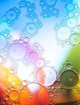 Bubbling liquid against multicolored background Stock Photos