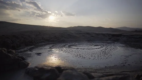 Bubbling mud volcano in lunar landscape. Sun reflection inside the crater. Stock Footage 105176447