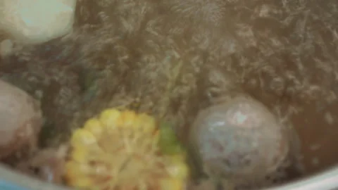 Bubbling pot boiling corn and carrots with steam swirls, cooking process Stock Footage 300855390