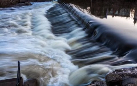 A bubbling river with a rapid and reflection of buildings in early spring Stock Photos