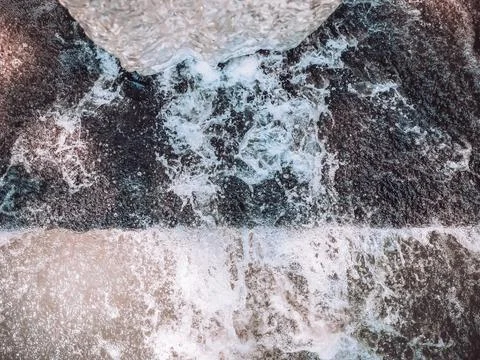 A bubbling stream of clear water flowing from top to bottom into a foamy Stock Photos