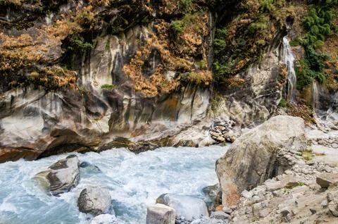 Bubbling water in a riverbed between rocks. Stock Photos