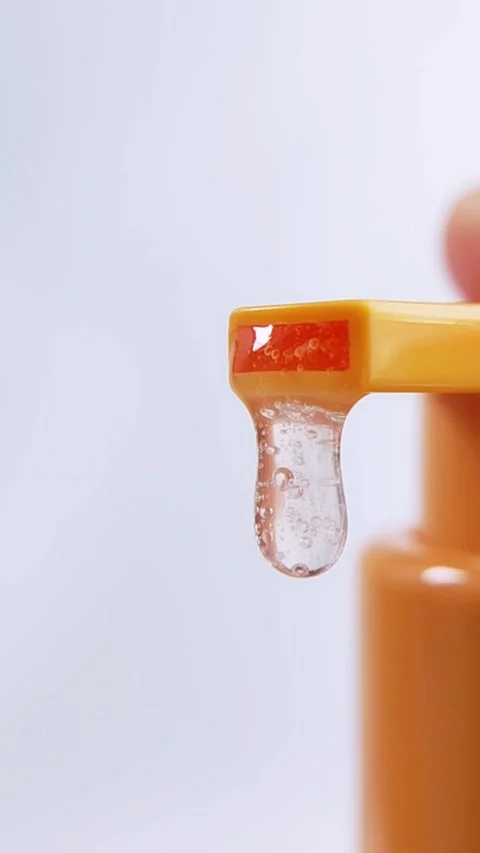 Bubbly clear liquid being pumped out from orange product packaging. Vertica.. Stockbeeldmateriaal 336238751