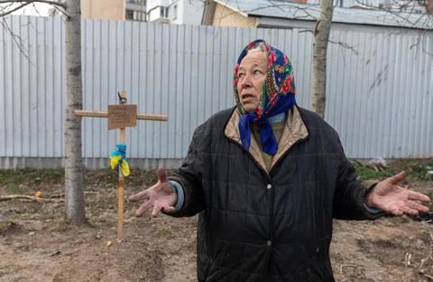 Bucha, Ukraine. Local woman near the grave of her relatives Stock Photos