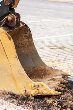 The bucket of a bulldozer is filled with a large quantity of dirt Stock Photos