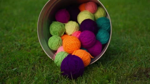 Bucket with colored balls of thread on the grass outdoors. Balls Of Wool Stock Footage 198186725