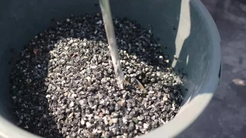 Bucket filled with black and gray gravel under bright sunlight Stock Footage 341584103