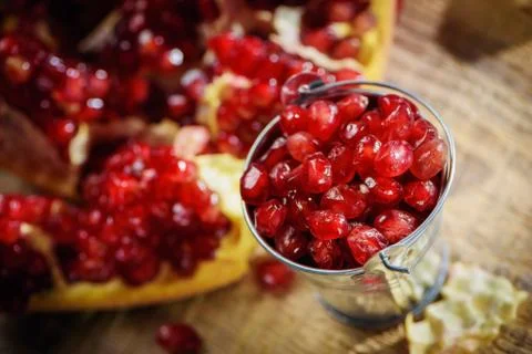 A bucket of fresh ruby red pomegranate beans on old rustic wooden table Stock Photos