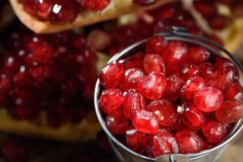A bucket of fresh ruby red pomegranate beans on old rustic wooden table 2 Stock Photos