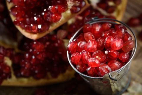 A bucket of fresh ruby red pomegranate beans on old rustic wooden table 3 Foto stock