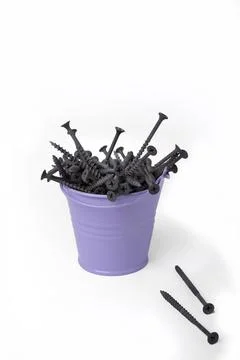 A bucket full of black self-tapping fasteners on a white background. Isolated Stock Photos