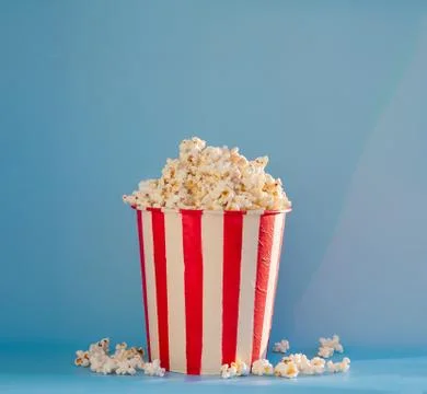 A bucket full of popcorn on a blue background Stock Photos