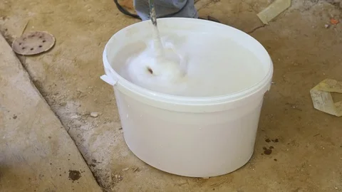 Bucket with lime paint being stirred with a stir paddle Stock Footage 71085508