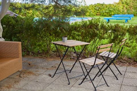 A bucket of pine cones on an empty garden table and two chairs Stock Photos
