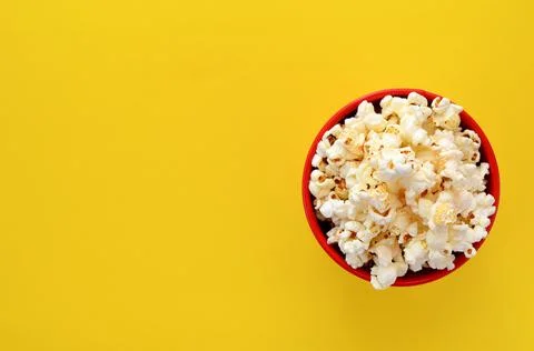 A bucket of popcorn on a yellow background flat lay, copy space Stock Photos