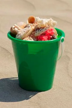 A bucket of seashells at the beach Stock Photos