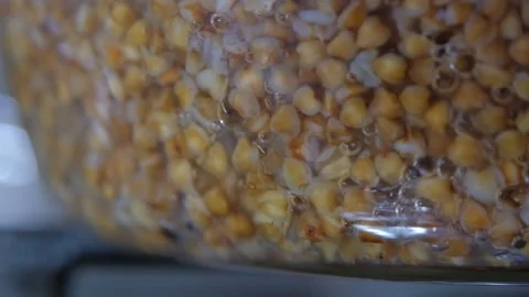 Buckwheat cooking process. Buckwheat is cooked in a transparent glass pan Stock Footage 283815781