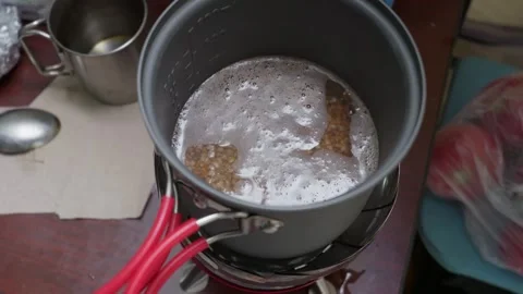 Buckwheat Groats Boiling in Cooking Pot on Portable Camping Stove Stock Footage 341993875