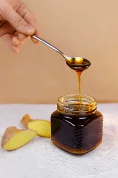 Buckwheat honey pours from spoon into jar Stock Photos