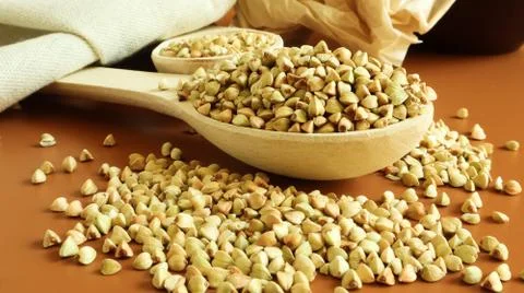 Buckwheat scattered background, raw green cereal in a wooden spoon. Healthy g Stock-Fotos