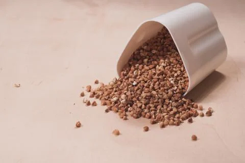 Buckwheat is scattered from the white container Stock Photos