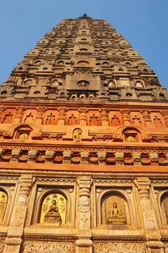 Buddha carved in different aspect on wall and soaring tower of Mahabodhi t... Stock Photos