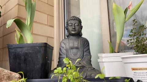 A Buddha statue on a balcony, surrounded by plants Video stock 128332222
