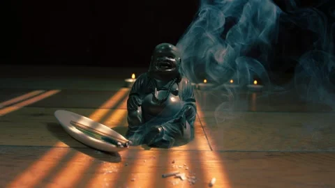 Buddha statue with candles and incense sticks in dappled light Video stock 344747342
