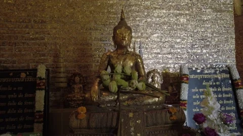 Buddha statue covered in gold leaf, with golden background and Thai script Stock Footage 234593629