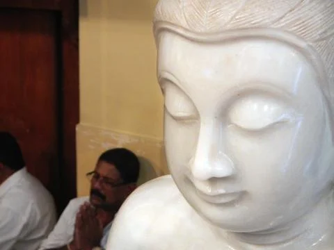 Buddha statue inside of the Kandy temple, behind people praying Stock Photos