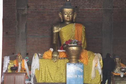 Buddha statue made up of bronze material, with brick wall background Stock Photos