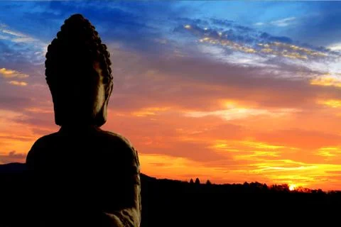 Buddha Statue Silhouette with blue and yellow sky background Stock Photos