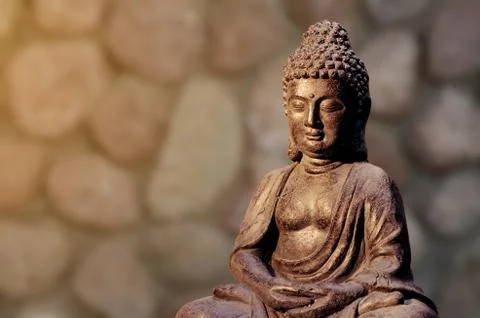 Buddha statue sitting in meditation pose against blurred background. Stock Photos