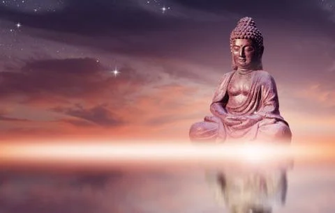 Buddha statue sitting in meditation pose against sunset sky with golden tones Stock Photos