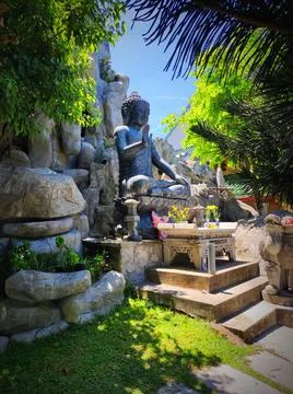 Buddha statue surrounded by greenery at a garden in the daytime Stock Photos