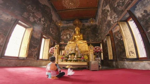 Buddha statue at Wat Bowonniwet Wihan temple with women sitting in front praying Stock Footage